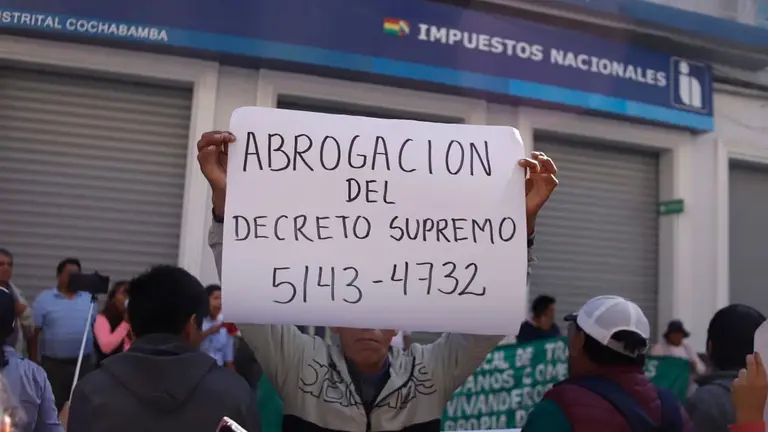 Una persona del sector gremial levanta un cartel exigiendo la abrogaci&oacute;n de dos Decretos Superemos frente a la oficina de Impuestos Nacionales. APG