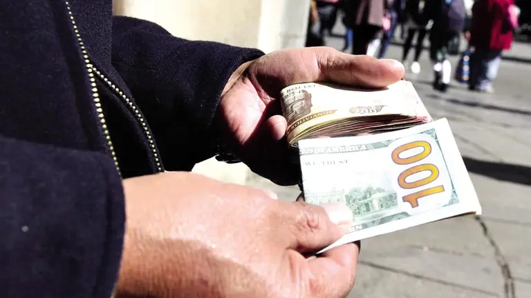 Un hombre sostiene dólares y bolivianos, tras una transacción. / LA RAZÓN