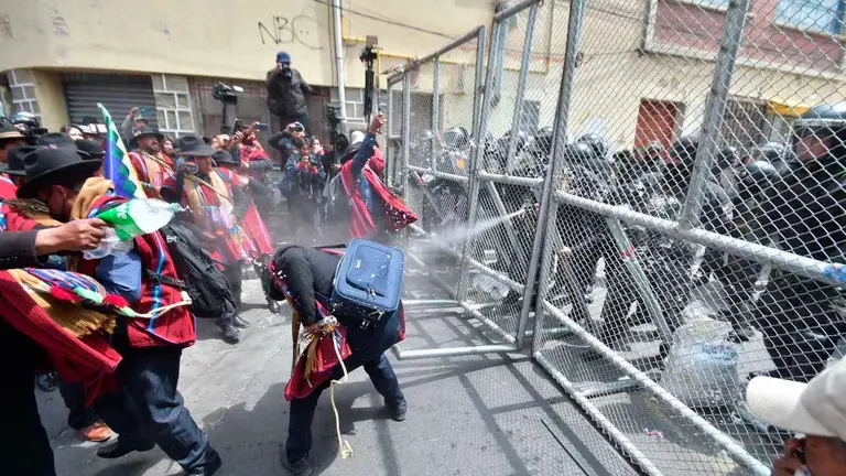 Momento en que efectivos de la Polic&iacute;a roc&iacute;an con gas lacrim&oacute;geno a los Ponchos Rojos. APG