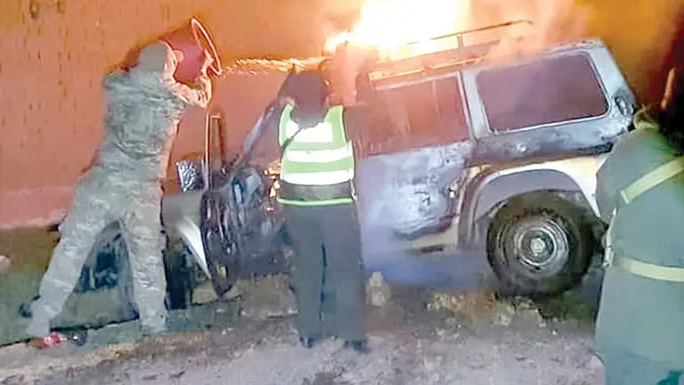 Personal militar y policial trata de sofocar el fuego en el veh&iacute;culo./ ABI