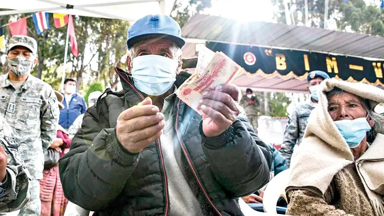 Un beneficiario muestra su dinero tras haber cobrado en una entidad bancaria./ ABI