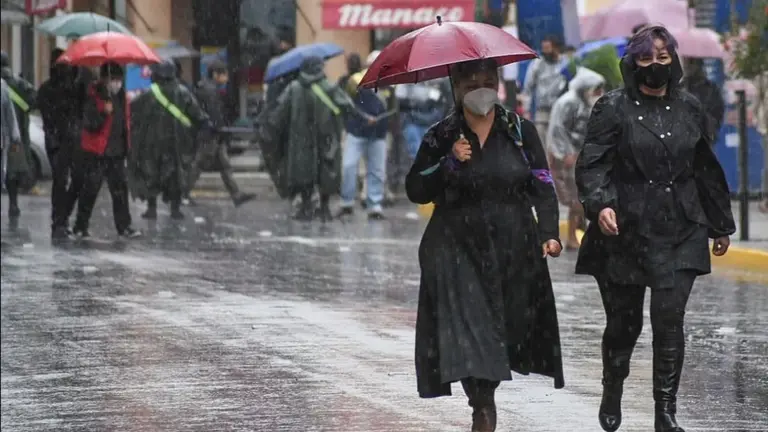 Personas se protegen de la lluvia en una c&eacute;ntrica calle de la ciudad.  ARCHIVO