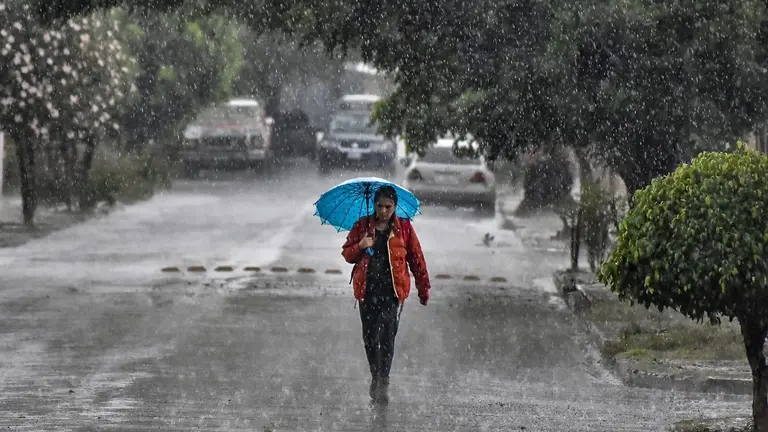 Una mujer se protege de la lluvia con un paraguas. CR&Eacute;DITO: ARCHIVO
