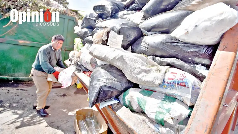 Una persona deja basura en un contenedor repleto./ DICO SOL&Iacute;S