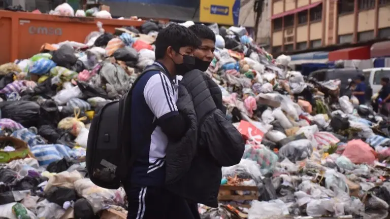 Dos ciudadanos transitan por las calles de la ciudad invadida por la basura, a principios de abril. DICO SOL&Iacute;S