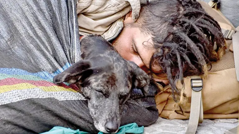 Un indigente duerme juntos a un perro, en la calle./ DICO SOLÍS