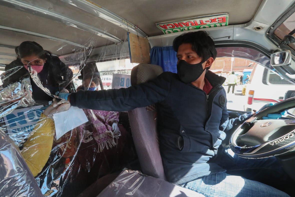 Un conductor cobra el pasaje, en medio de medidas de bioseguridad. APG
