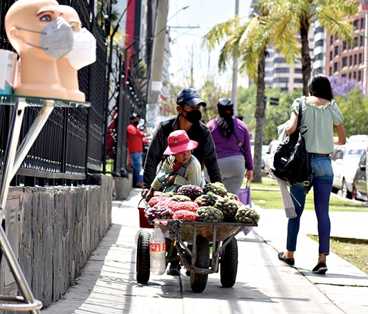 Un hombre empuja una carretilla en la que lleva papas para vender.