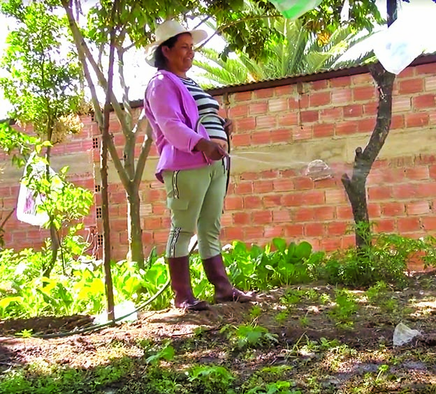 Una de las productoras riega su huerto en su casa. LA BRAVA