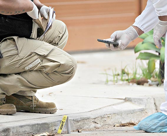 Los investigadores recolectan evidencias en la entrada del inmueble del capitán asesinado. / APG