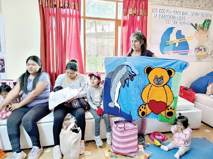 Una madre muestra una alfombra hecha a mano para su hijo. / DAYANA FLORES